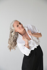 lifestyle portrait senior woman  with gray hairrelaxes wearing a white shirt and black trousers  against a gray background.  copy space. greyhairdontcare. banner