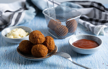Fried meatballs in a bowl with ketchup on the side.