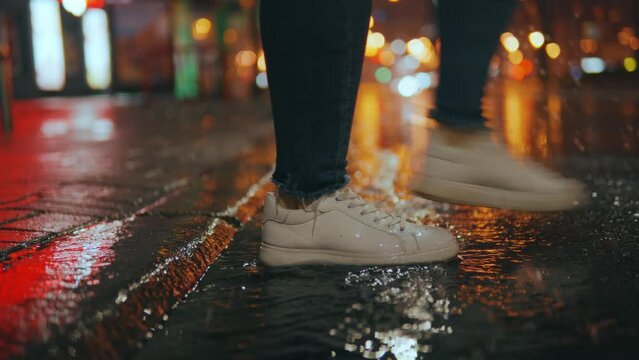 Close-up of a woman's feet stepping into a muddy puddle and making a splash
