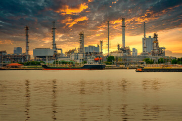 Naklejka premium An oil refinery located on the Chao Phraya River, in Bangkok, Thailand, is a large industrial factory. and the golden evening sky has Big clouds when it's about to rain