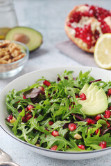 A plate with green rocket salad with pomegranate	 and avocado
