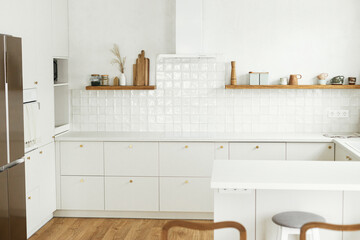 Modern kitchen interior. Stylish white kitchen cabinets with brass knobs, granite island,...