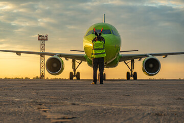 Airport worker standing in front of the airplane at the airport.
