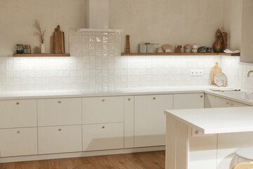 Modern kitchen interior. Stylish white kitchen cabinets with brass knobs, granite island,...