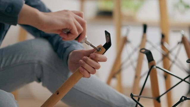 Woodwork, Business owners In process Assembles furniture by screwing a screw with a screwdriver In a workshop A young mother girl Performs furniture repairs Stands in front of work surface, carpenter
