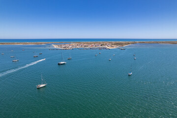 Fototapeta na wymiar Aerial seascape view of Culatra island fishing port and beach, one of the barrier islands that protect the Ria Formosa natural park, in Algarve Tourism Destination Region, in Portugal south coast.