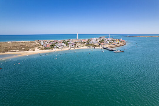 Aerial seascape view of Cape Santa Maria lighthouse island, Praia do Farol beach, one of the barrier islands that protect the Ria Formosa natural park, in Algarve Tourism Destination region, Portugal