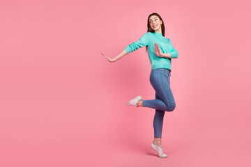 Fototapeta na wymiar Having Fun. Portrait of happy young woman dancing looking aside free space being good mood isolated over pink background