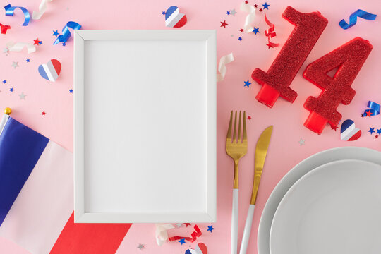 Bastille Day-themed table setting. Top view photo of plates, cutlery, shiny number 14, french flag, hearts, patriotic sparkles on pastel pink background with blank frame for advert or text