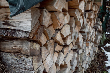 A supply of tree trunks have been stacked and is located on the side of the path and is with a...