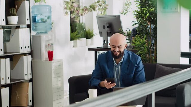 Startup worker using smartphone at work, sitting in coworking space before examining statistics for research project. Analyst working with device to find records for business partnership. Tripod shot.