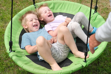 Grandfather swinging children in summer park. Grand dad and grandchildren sitting on swing...