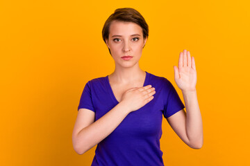 Photo portrait of serious young woman hand on chest promising tell truth isolated yellow color...