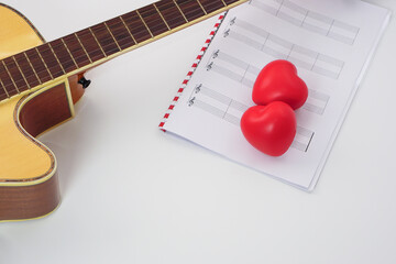 Focus the acoustic guitar neck and blur musical notes and red heart on white background. Love,...