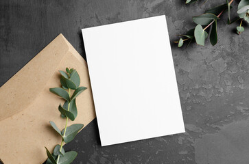 Invitation or greeting card mockup with fresh eucalyptus twigs and envelope on dark background © nikavera