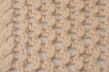 A fragment of beige knitted fabric, knitted from white sheep wool.