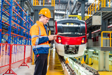 Caucasian male engineer wearing uniform and helmet standing holding smartphone typing social...