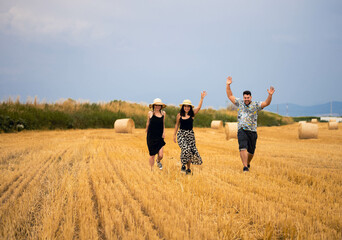 A group of friends running in a field with hay bales