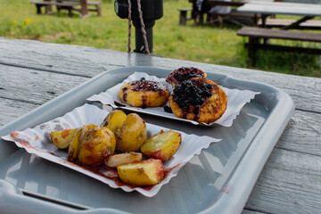 Fried potatoes and cheese dessert with fruits during an outdoor picnic.