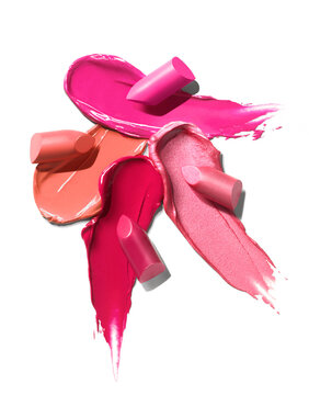 Red pink orange shimmering lipstick glossy texture strokes with lipstick bullets isolated on white background. Cosmetic product swatch