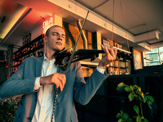 Violinist in jacket play violin in bar or restaurant, musical performance.