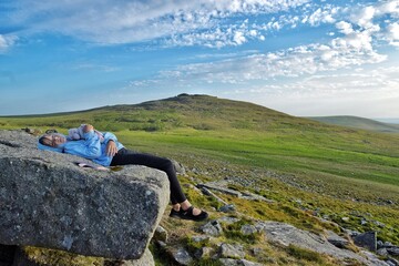 A young girl relaxing on a huge granite rock in Dartmoor National Park. 