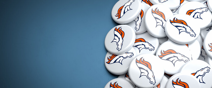Logos of the American Football Team Denver Broncos on a heap on a table.