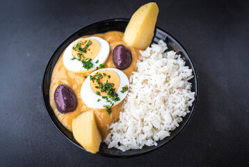 Aji de gallina or Peruvian curry is a comfort chicken stew served with rice at the table. Top horizontal view from above