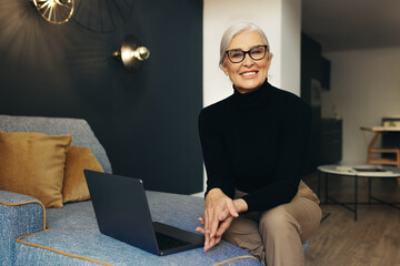 Experienced female freelancer sitting on a couch with a laptop during work