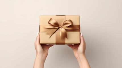 A person holding a gift box with a brown ribbon