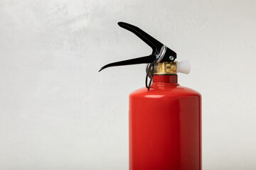 Obraz premium Fire extinguisher on a light texture background. Fire protection, home fire extinguisher. home security concept. Place for text. Copy space.banner