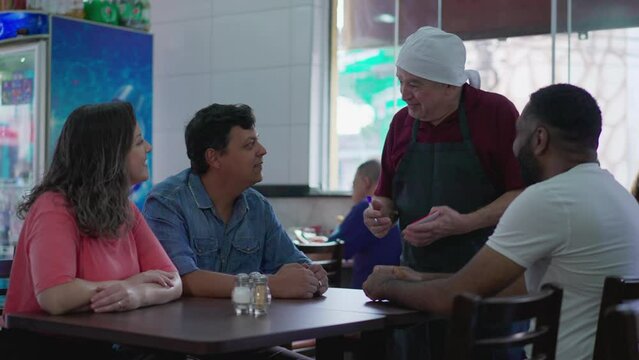 Restaurant Local Business Scene of Senior Waiter speaking with customers, taking orders and interacting with clientele