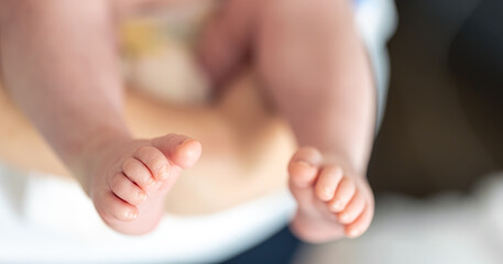 Close-up, the feet of a newborn in the hands of the mother.