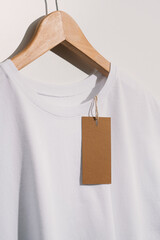 White t-shirt with blank price tag on wooden hanger