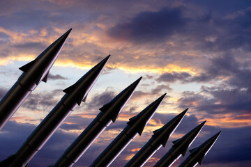 Row of nuclear ballistic missiles in silhouette ready to be launched at sunset. Illustration of the concept of nuclear wars and World War III - obrazy, fototapety, plakaty