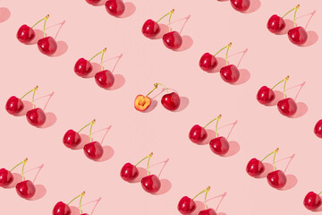 Fresh juicy cherries, creative fruit pattern, dusty rose pink background. 