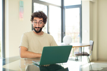 young adult bearded man with a laptop wondering, thinking happy thoughts and ideas, daydreaming, looking to copy space on side