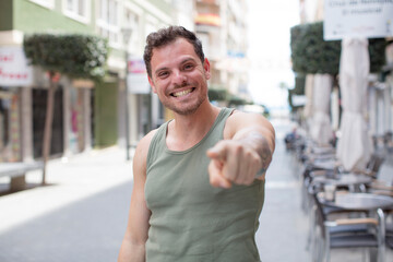 Fototapeta na wymiar handsome man pointing at camera with a satisfied, confident, friendly smile, choosing you