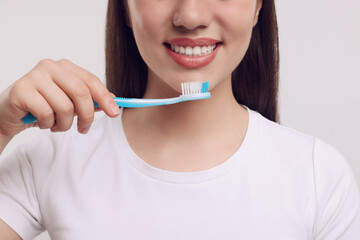 Woman holding plastic toothbrush on white background, closeup