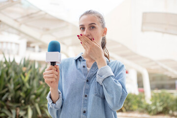 covering mouth with a hand and shocked or surprised expression. presenter with a microphone concept