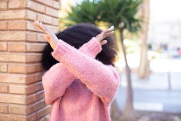 african american pretty woman covering face with hand and putting other hand up front to stop...