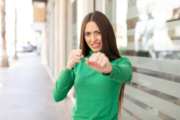 young pretty woman looking confident, angry, strong and aggressive, with fists ready to fight in boxing position