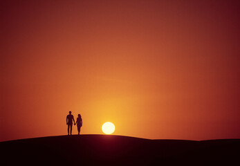 Fototapeta na wymiar Couple walking towards the sun at sunset