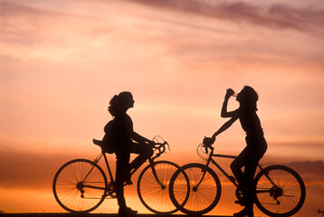 Two teenage girls on bicycles at sunset