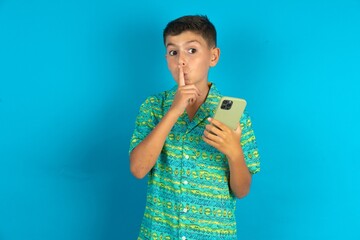 Little hispanic boy wearing green aztec shirt holding modern gadget ask not tell secrets