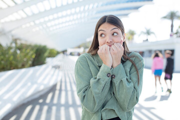 Fototapeta premium young pretty woman looking worried, anxious, stressed and afraid, biting fingernails and looking to lateral copy space