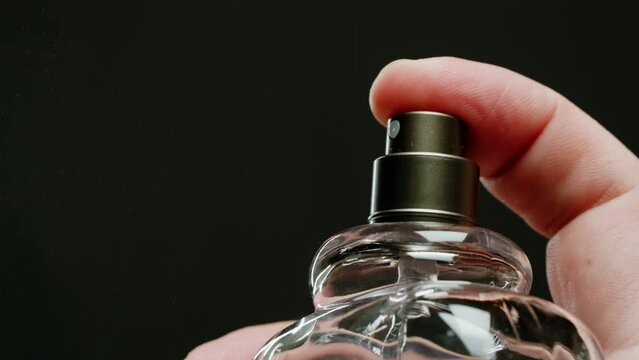 Young man applying perfume to skin in the dark, close up of spraying deodorant luxury perfume.
