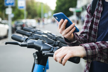 Close up of man hand using mobile app for rental electric scooter.