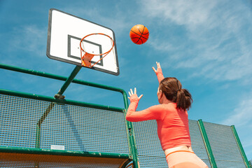 Female basketball player about to throw at the hoop. Outdoors in the sun