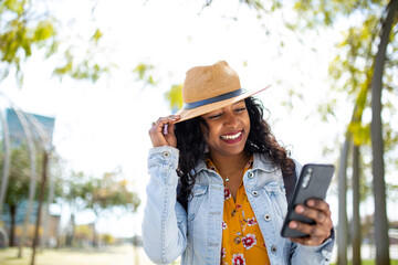 Beautiful young african american woman with hat looking at cell phone